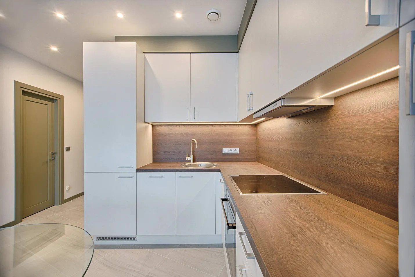 A kitchenette with white cupboards and a wooden counter.